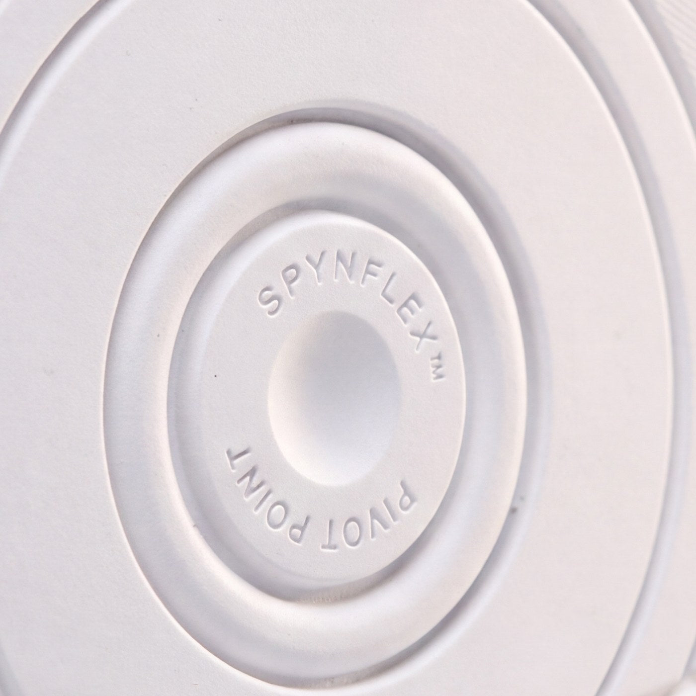 The SPYNFLEX® pivot disc in close-up, showing the molded mark and the rings around it.